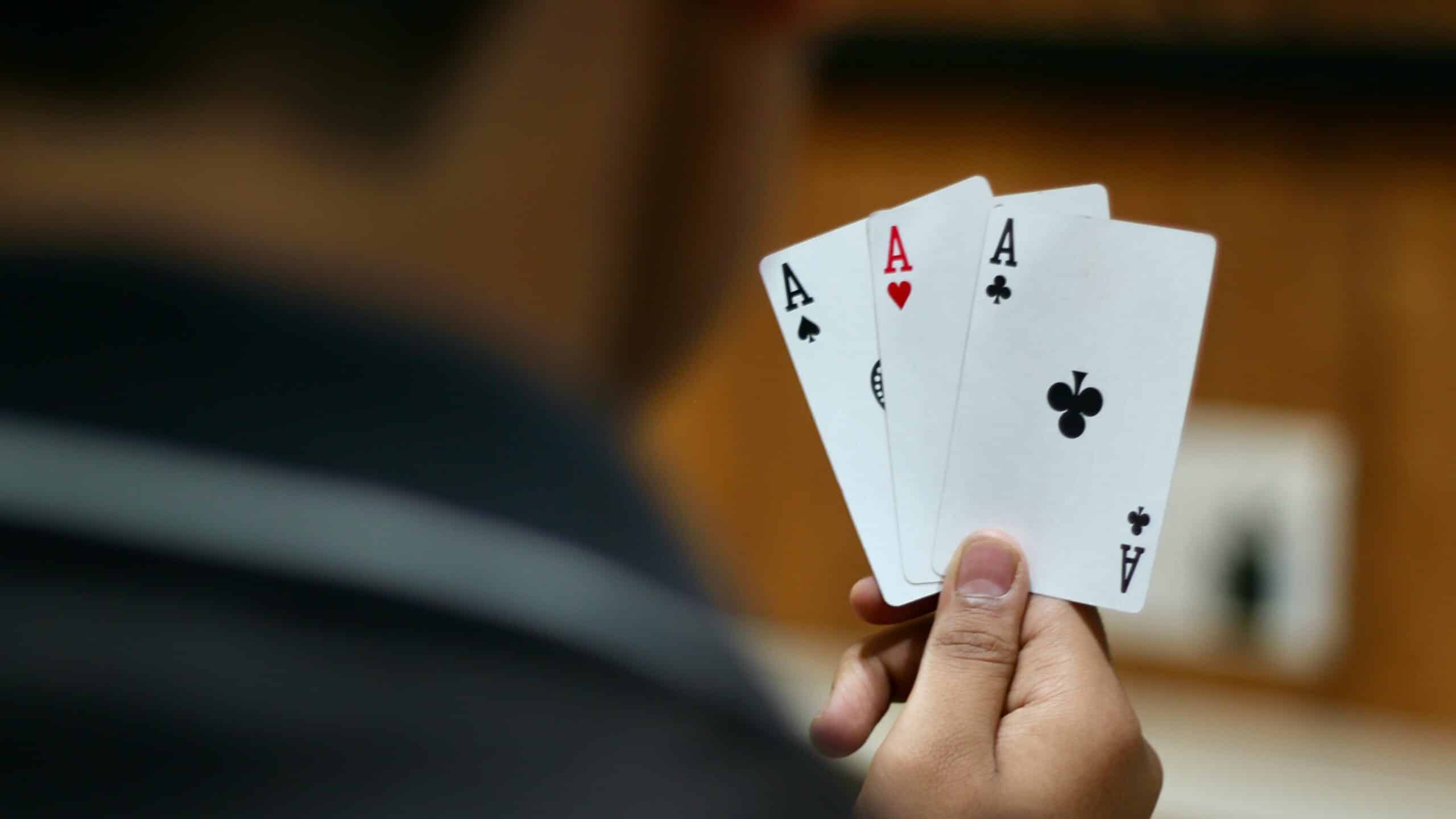 person holding three ace cards