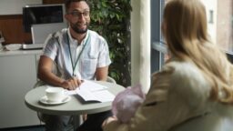 Two people sitting at a table with paperwork potentially reviewing unclaimed benefits, entitlement, and energy or utility bills