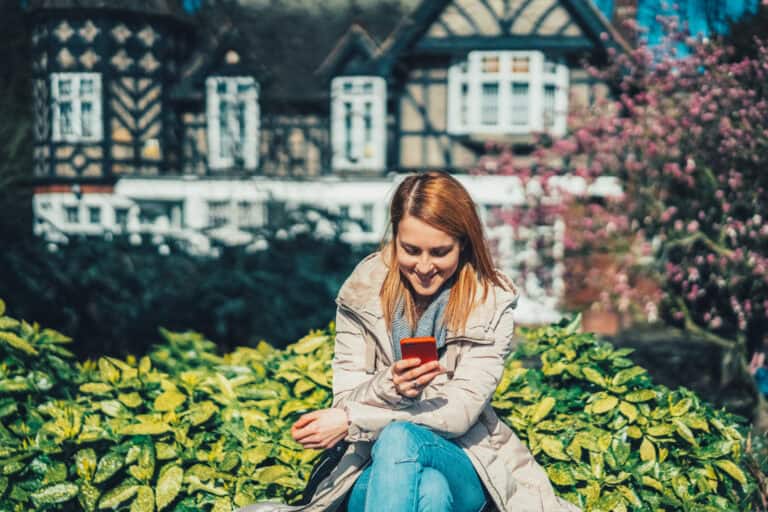 Woman using mobile phone outdoors, promoting savings with London Mutual Credit Union.