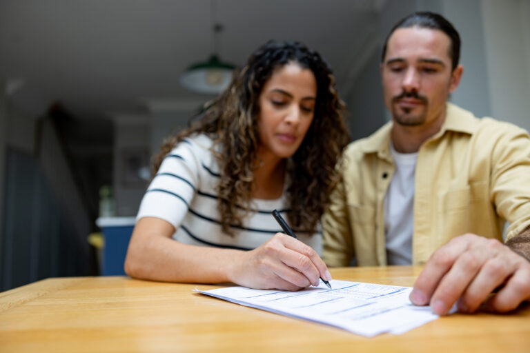 Close-up on a couple signing a transfer of equity agreement as part of legal proceedings following a divorce