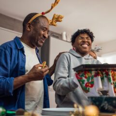 Two people enjoying Christmas Day together, sharing food and laughter, representing the joy of saving money at Christmas through thoughtful spending.