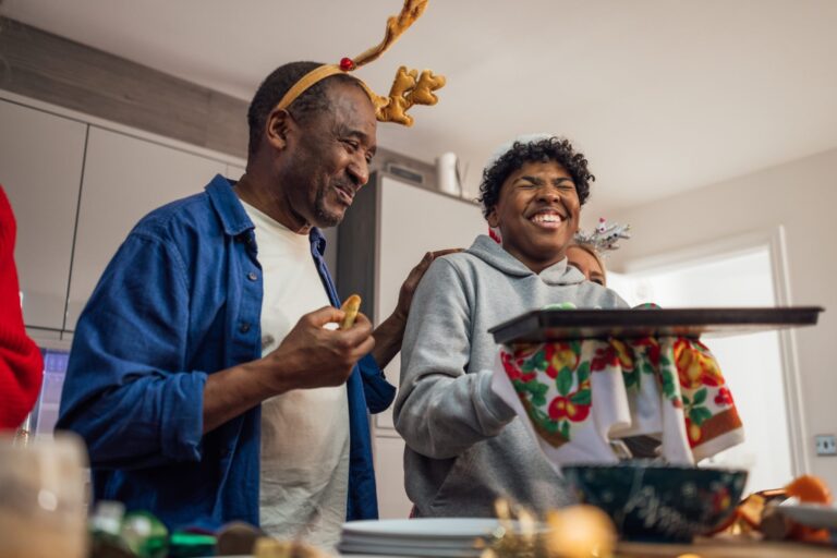 Two people enjoying Christmas Day together, sharing food and laughter, representing the joy of saving money at Christmas through thoughtful spending.